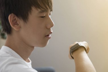 Genç Asyalı adam akıllı saat kullanıyor..