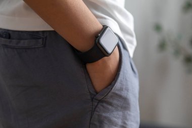 Genç Asyalı adam evde akıllı saat kullanıyor.