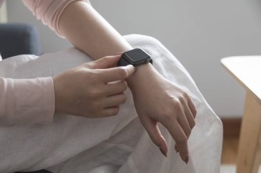 Kadın eli akıllı saati tutuyor.