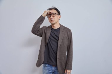 Genç Asyalı adam gözlük takıyor ve beyaz arka planı olan kameraya bakıyor.