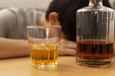 İçerideki masada elinde votka ve cam şişesi olan sarhoş adam.