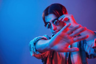 Looking into camera. Man standing in the studio with neon light.