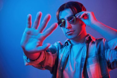 Looking into camera. Man standing in the studio with neon light.