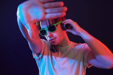 Dj is having fun. Man standing in the studio with neon light.