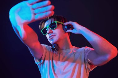 Dj is having fun. Man standing in the studio with neon light.