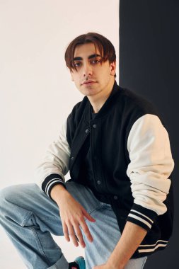 Young man is in the studio with white and black walls.