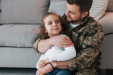 Savunma ve güvenlik kavramı. Üniformalı asker küçük kızıyla evde..
