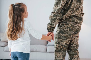 Babamın elini tutarak. Üniformalı asker küçük kızıyla evde..