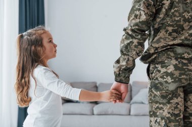 Babamın elini tutarak. Üniformalı asker küçük kızıyla evde..
