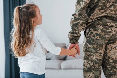 Babamın elini tutarak. Üniformalı asker küçük kızıyla evde..