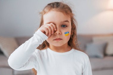 Masum bir çocuk ağlıyor. Yüzünde Ukrayna bayrağı olan küçük bir kızın portresi.