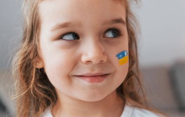 Gülümsüyor ve keyfim yerinde. Yüzünde Ukrayna bayrağı olan küçük bir kızın portresi.