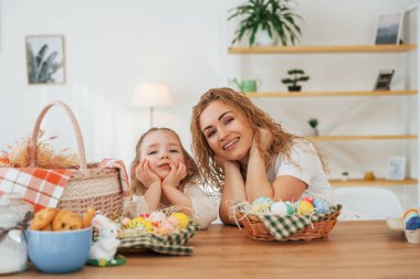 Gülümsüyor ve eğleniyor. Mutlu anne ve kız Paskalya tatillerini birlikte kutluyor..