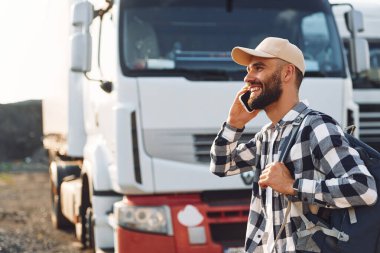 Gülümsüyor, telefonla konuşuyor. Genç kamyon şoförü gündüz vakti aracıyla geliyor..