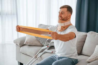 Silahlar için rehabilitasyon egzersizleri. Koltuk değnekli adam evde. Yaralı..