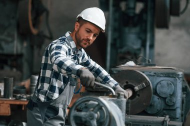 İşletim makinesi. Üniformalı fabrika çalışanı içeride..