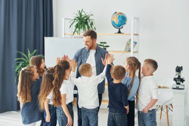 Dersin sonunda beşlik çakıyorsun. Okulda öğretmenle birlikte bir grup çocuk öğrenci..