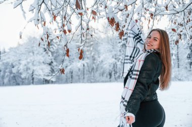 Durup poz vermek. Güzel genç bir kadın kış ormanında dışarıda..