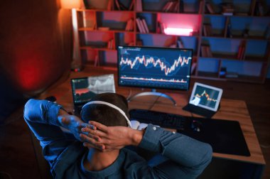 Hisse senedi tüccarı kapalı alanda bilgisayar başında çalışıyor. Değişim ve para kavramı.