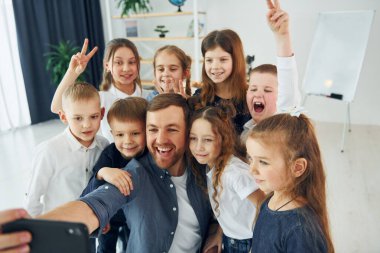 Making a selfie by phone. Group of children students in class at school with teacher.