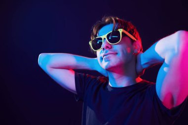 Feeling relaxed. Man standing in the studio with neon light.