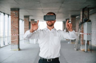 İnşaat alanında. Resmi kıyafetli adam binada VR oyunu oynuyor..