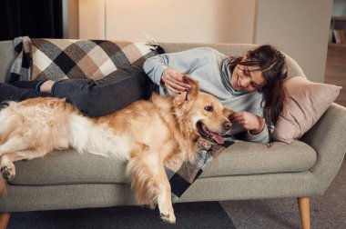 Birlikte kanepede uzanıyorduk. Kadın Golden Retriever köpeğiyle evde..