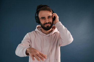 Kulaklıklı DJ. Yakışıklı adam stüdyoda mavi arka planda..