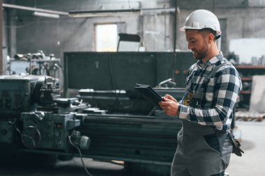 Siyah renkli grafik tablet tutuyordu. Üniformalı fabrika çalışanı içeride..