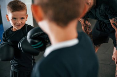 Alıştırma yaparak eğleniyorum. Genç dövmeli koç çocuklara boks teknikleri öğretiyor..