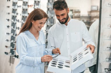 Değiştirilebilir lensleri tutuyorum. Gözlükçüdeki kadın ve erkek. Ürün seçimine yardım etmek.