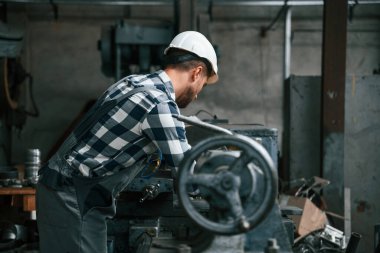 Endüstri makinesini manipüle etmek. Üniformalı fabrika çalışanı içeride..