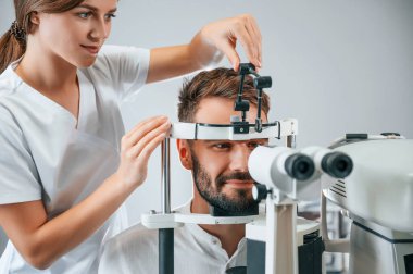 Özel optometrist cihaz kullanarak klinikteki kadın doktor tarafından erkeğin görüşü kontrol edildi..