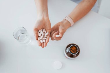 Elinde haplar olan kadınların en iyi görüntüsü. Ofiste beyaz önlüklü profesyonel bir sağlık görevlisi var..