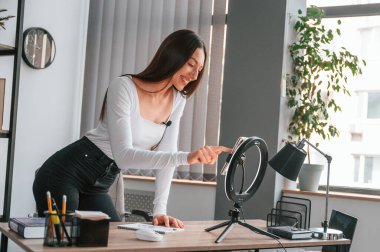 Akıllı telefonu kayıt için kuruyorum. Beyaz elbiseli genç ve güzel bayan ofiste..