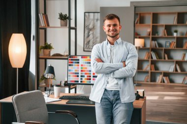 PC 'ye karşı durmak. Genç erkek tasarımcı modern ofiste..