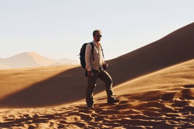 Durup poz vermek. Günlük giysiler içindeki erkek turist Afrika çöllerinde, Namibya 'da..