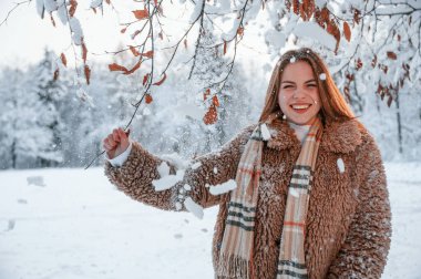 Karla kaplı ağacın dallarının altında duruyorlardı. Güzel genç bir kadın kış ormanında dışarıda..