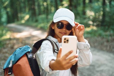 Telefonla selfie çekiyorum. Kız yaz günü ormanda yeni yerler keşfediyor..