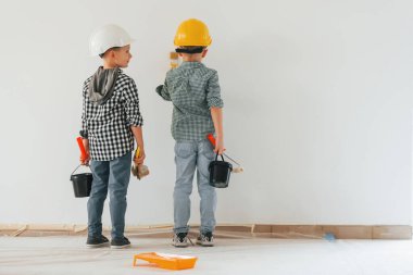 Dikiz aynası. İki çocuk ev odasında duvar boyuyor..
