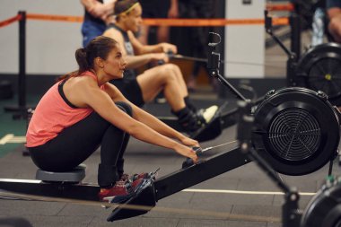Yan görüş. Spor salonunda kürek çeken sporcu bir kadın..