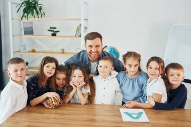 Durup poz vermek. Birlikte gülümsüyoruz. Okulda öğretmenle birlikte bir grup çocuk öğrenci..