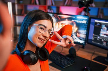 Gülümsemek, zafer jestleri yapmak ve selfie çekmek. Genç ve güzel oyun flaması bilgisayarla birlikte içeride..