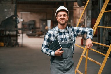 Merdivene yaslan. Üniformalı fabrika çalışanı içeride..