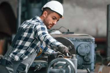 İşletim makinesi. Üniformalı fabrika çalışanı içeride..