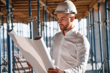 Ayakta ve okuma planı. Gündüz vakti inşaatta çalışan bir adam var..