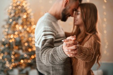 Ayakta durmak ve el ele tutuşmak. Güzel genç çift yeni yılı evde kutluyor..