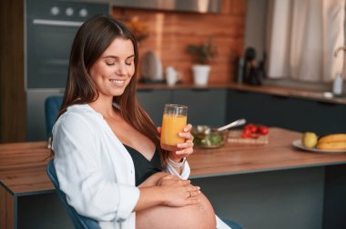 Portakal suyuyla. Güzel hamile kadın evde..