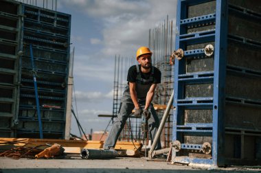 Matkabı kullanarak. Üniformalı adam inşaat alanında çalışıyor..