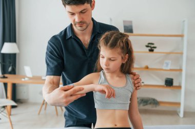 Profesyonel fizyoterapist çocuk kollarına Kinesio bandı yapıştırıyor..